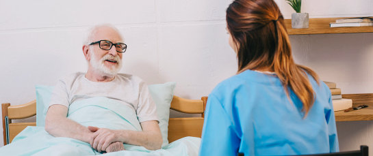 senior man on bed talking to a caregiver