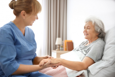 caregiver massaging hand of senior woman at home