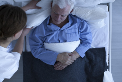 young nurse correcting the cushion for senior patient lying on a hospital bed