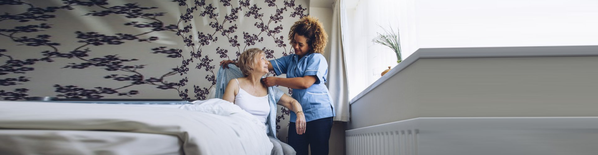 caregiver helping senior woman get dressed